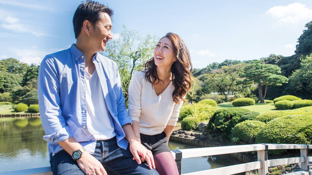 asian man and woman smiling in front of garden