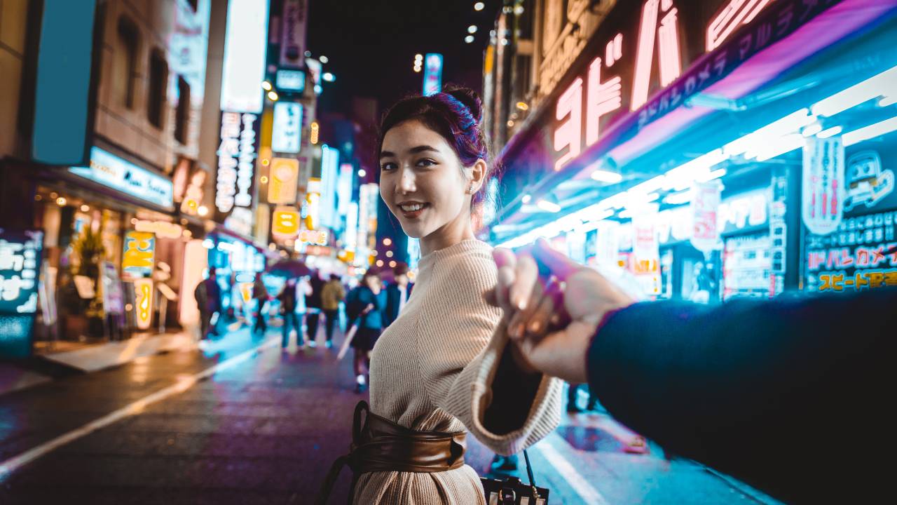 asian woman smiling looking back at camera holding a man's hand