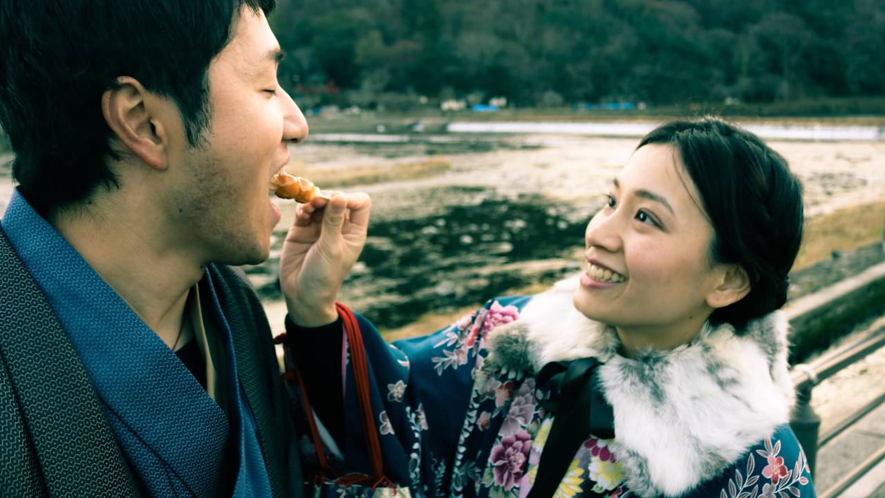 Woman wearing kimono feeds man wearing kimono