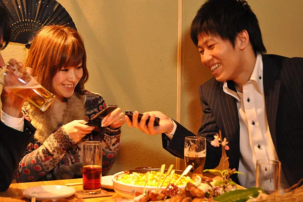A seated Japanese couple mingling and exchanging information while drinking and experiencing Shibuya Nightlife.