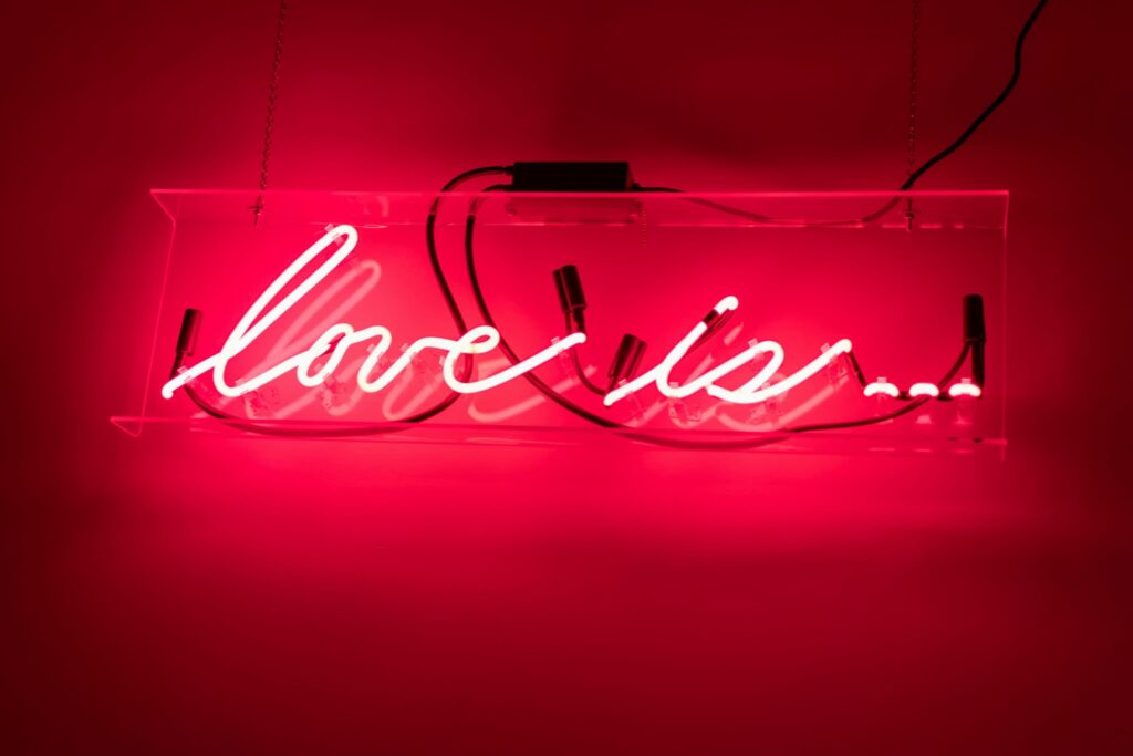 A red neon sign that says "love is..."