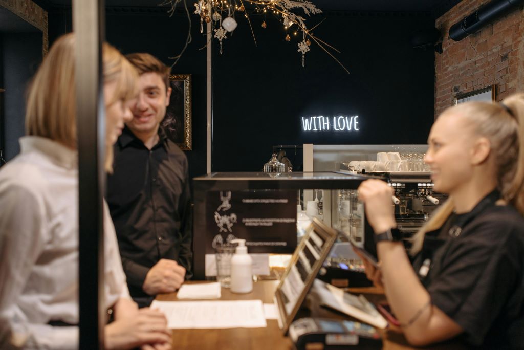 A man and a woman laughing with the bar staff while ordering at the bar counter.