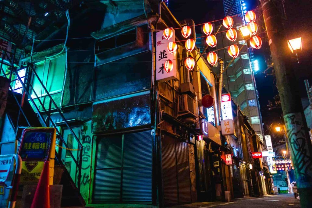 Street corner lit by japanese lanterns which is common sight for people living in Tokyo. There is also graffiti visible on some of the buildings.