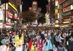 Crowded streets of people in costumes drinking on halloween experiencing Shibuya nightlife